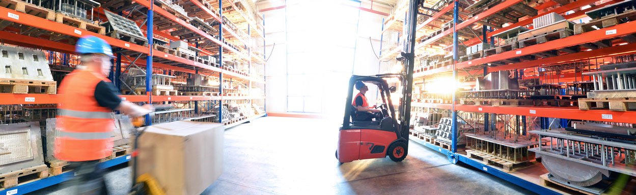 Logistik im Warenlager – Arbeiter mit Hubwagen und Gabelstapler